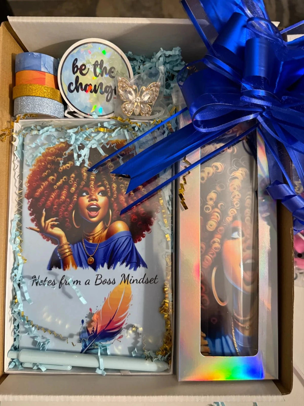 Boss Mindset gift set with blue afro journal, matching tumbler, blue bow, washi tape, 'Be the Change' sticker, and butterfly pin in gift box.