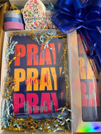 Unboxing gift set featuring a bold “Pray On It, Over It, Through It” journal and matching tumbler in navy, pink, and yellow with decorative ribbon and washi tape.