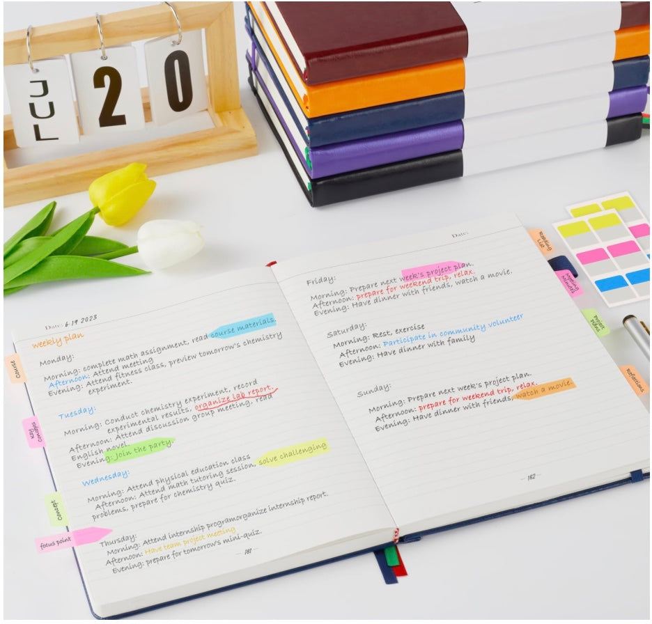Open journal displaying a weekly planning spread with color-coded notes, tabs, and organized handwritten entries on a desk.